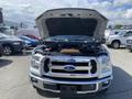 A 2015 Ford F-150 with its hood raised showcasing the engine compartment