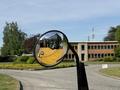 A 2022 Caterpillar 306 excavator is reflected in a convex mirror with its yellow arm and bucket prominently visible