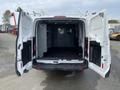Rear view of a 2017 Ford Transit van with open double doors showcasing an empty cargo area with metal shelving units and a partition