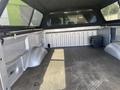 An empty truck bed of a 2014 Ford F-150 with a textured floor and two plastic storage bins in the corners