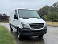 A 2016 Mercedes-Benz Sprinter van with a white exterior and black accents parked on a wet surface