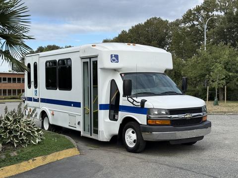 A 2015 Chevrolet Express cutaway van with a wheelchair accessibility feature and blue stripes on the side