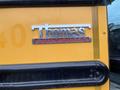 A close-up of the Thomas Built Buses logo on a yellow school bus with a black frame