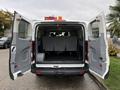 A 2018 Ford Transit van with its double rear doors open revealing a spacious interior with several gray seats arranged in rows