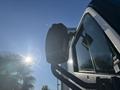 A 2022 Lion Lion6 truck with a side mirror visible in the foreground against a bright sky