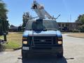 A blue 2008 Ford E-350 van with a bucket truck attached on top and warning lights mounted on the roof