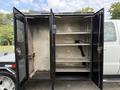 A 2008 Ford F-450 SD with open storage compartments revealing metal shelves and internal wiring