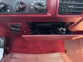 The interior dashboard of a 1995 Ford F-250 showing climate controls a power outlet and a storage compartment with a removable cover