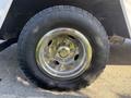 A close-up of a shiny chrome wheel with a rugged all-terrain tire featuring deep treads, mounted on a 2012 Ford Econoline E-450