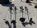 Four Shindaiwa gas powered weed eaters with straight shafts and different cutting attachments laid out on a surface