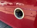 A fuel fill port with a metal frame on a red surface resembling a truck or vehicle body