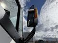 A close-up of the side mirror of a 2022 Lion Lion6 featuring a rectangular shape and an integrated light on the side