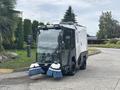 A 2019 Madvac LS175 street sweeper with two rotary brushes in the front and a compact, enclosed cab for the operator