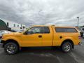 A bright yellow 2014 Ford F-150 with a truck bed cover and chrome wheels visible from the side