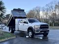 A white 2021 RAM 5500 dump truck with a raised bed showing its dumping mechanism