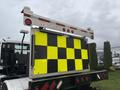 A 2016 Freightliner 108SD with a rear-mounted bright yellow and black checkerboard sign and warning lights