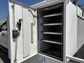 A 2017 Ford F-550 with an open compartment revealing multiple metal racks inside the spacious white enclosure