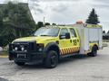 A 2010 Ford F-550 Super Duty emergency response vehicle painted yellow with red reflective stripes and equipped with a large side compartment for storage