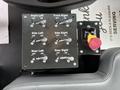 A control panel featuring multiple toggle switches labeled for front left front right side left side right rear left and rear right with a red emergency stop button