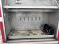 An empty compartment of a 2006 E-One Typhoon fire truck with metal walls and a metallic surface showing wear and tear
