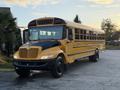 A yellow 2014 International 4300 school bus with a black front hood and large windows parked on a paved surface