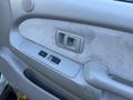 Interior door panel of a 2004 Toyota Tacoma featuring buttons for window control and a handle with a textured fabric surface