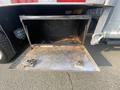 Open metal storage compartment with rusty bottom and two circular locks on the front attached to a truck
