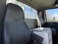 Two black leather seats in the cabin of a 2008 International 7500 truck with a small white storage unit between them