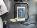 A blue electronic device mounted on a metallic plate inside a vehicle's cabin