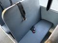 A grey bench seat from a 2014 International 4300 school bus with two black seat belts hanging on it and a third belt lying on the seat