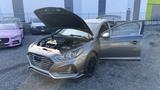 A 2018 Hyundai Sonata with its hood open revealing the engine compartment and the driver's side door ajar