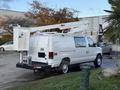 A white 2007 Ford Econoline van with an elevated bucket lift attached to the roof