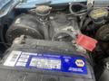 A close-up view of a car battery with labels and cables visible in the engine compartment of a 2009 Ford Econoline