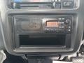 Dashboard of a 2010 Suzuki Carry featuring a radio display with buttons and an open storage compartment below