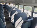 Interior view of a 2006 Thomas Saf-T-Liner HDX school bus with blue seats arranged in rows and sunlight casting shadows on the floor