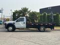 A white 2009 Ford F-450 Super Duty flatbed truck with visible utility equipment on the bed parked on a concrete surface