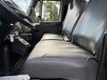 The interior of a 2011 International 4300 featuring a black leather bench seat with two sections visible from the side angle