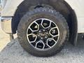 A close-up of a 2021 Ford F-150 tire showcasing a large black rim with silver accents and all-terrain tread pattern