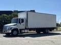 A 2020 Hino 338 truck with a white box cargo area and a silver front grill parked on a lot with trees nearby