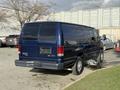 A blue 2011 Ford Econoline van is parked, showcasing its rear view and side profile with a simple design and large rear windows.