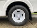 A close-up of the white wheel and tire of a 2015 Chevrolet Express featuring a Firestone Transforce HT tire with a textured tread pattern