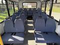 Interior view of a 2017 Chevrolet Express featuring rows of blue upholstered seats arranged in a spacious layout with seat belts
