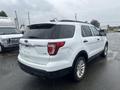 A white 2016 Ford Explorer parked on a wet surface showing its rear and side profile with a black roof and chrome accents