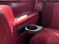 A cup holder protruding from the armrest of a red interior 1995 Ford F-250 truck seat