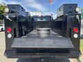 A black 2022 Ford F-350 SD truck with an open flatbed showing storage boxes on either side and a metal wheel placed in the center of the bed