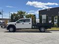 A white 2017 Ford F-550 flatbed truck is shown from the side with a crew cab and a black flatbed attached to the rear