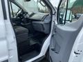 Interior view of a 2017 Ford Transit showing the driver's seat dashboard and passenger door with gray fabric and plastic finishes