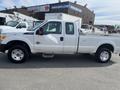A white 2014 Ford F-250 SD with a crew cab and a flatbed in the foreground