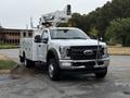A 2018 Ford F-550 truck with a white body equipped with a bucket lift on top and a utility service box on the side