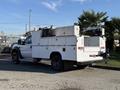 A white 2009 Ford F-550 truck with a utility service body featuring storage compartments and equipment mounted on the back